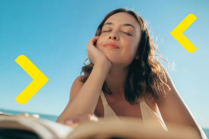 Smiling happy young woman giving her friend a lift in her car in town, profile view through the open side window with sun flare