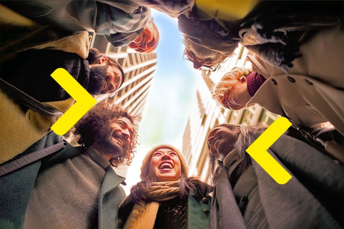 Smiling happy young woman giving her friend a lift in her car in town, profile view through the open side window with sun flare