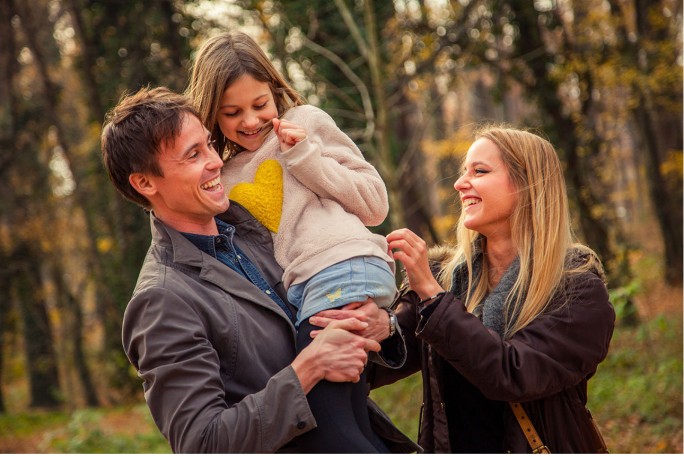 happy copule with dauther playling, smiling, in the park